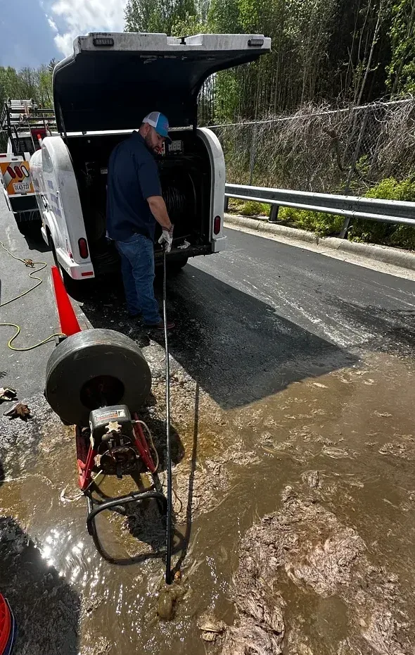 Technician operating drain-clearing equipment in an authentic supplied work photograph.