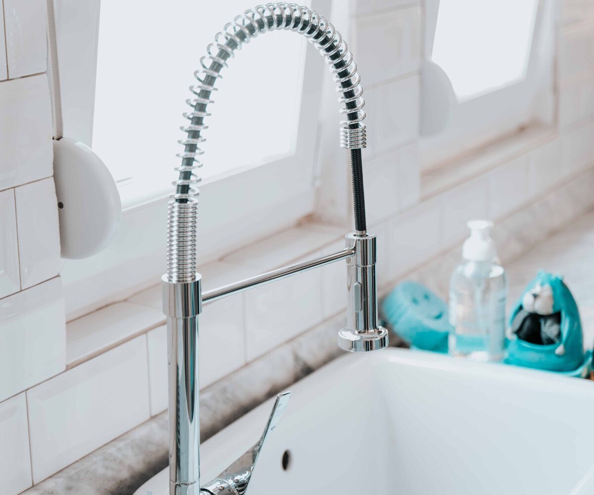 Representative stock photo of a clean white kitchen sink with a chrome faucet, illustrating sink plumbing service.